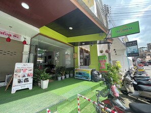 A salon with a green awning, a 'Room for Rent' sign, and a row of parked scooters. - T & C Hotel Patong Beach By Zuzu (Patong)