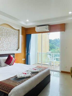 A hotel room with a large bed, a balcony with white chairs, and an air conditioning unit. - T & C Hotel Patong Beach By Zuzu (Patong)
