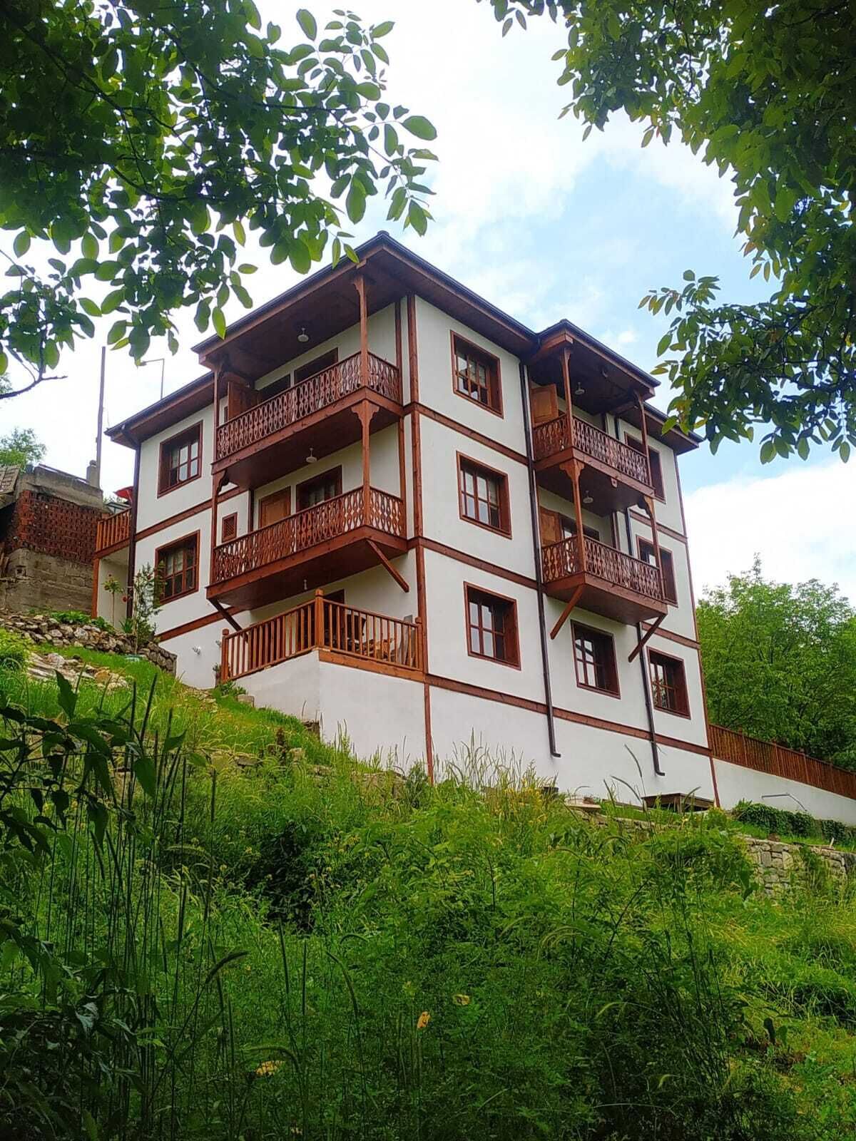 A multi-story building with balconies, surrounded by greenery.