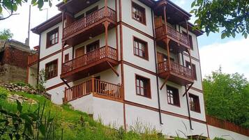A multi-story building with balconies, surrounded by greenery.