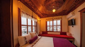 A cozy room with a large bed, a bench, and a view of a snowy landscape through the windows. - Manzara Konak Otel (Safranbolu)