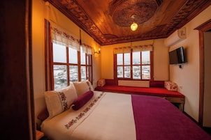 A cozy room with a large bed, a bench, and a view of a snowy landscape through the windows.