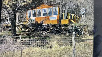Una cabaña de madera con un ventanal grande y una pequeña estructura adosada.