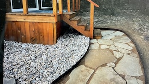 Una terraza de madera con un camino de piedra que lleva a una escalera de madera.
