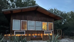 Una cabaña de madera con amplias ventanas y un sendero de piedra que conduce a la entrada.
