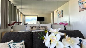 A bedroom with a bed, a TV, a window with curtains, and a painting on the wall. - Penthouse in Waikiki with ocean & mountain views 5 minutes walk to Waikiki beach (Honolulu)