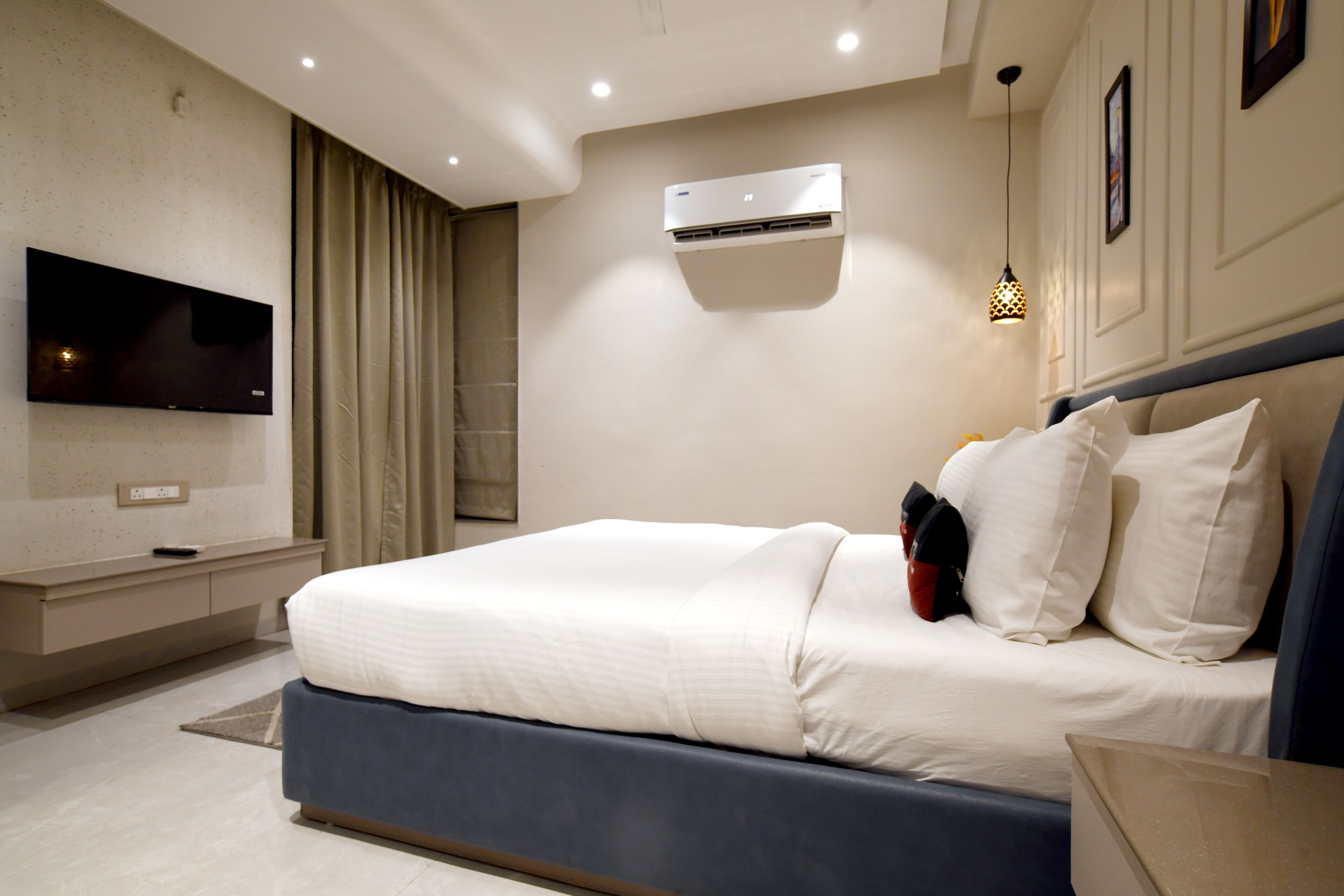 Une chambre moderne équipée d’un lit, d’un téléviseur à écran plat, d’un climatiseur et d’une table de chevet.