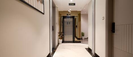 A modern hotel hallway with a marble floor, a lift, and a sign indicating the 2nd floor.