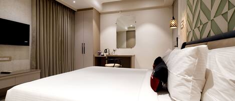 A modern hotel room with a large bed, a bedside table, a mirror, and a TV mounted on the wall.