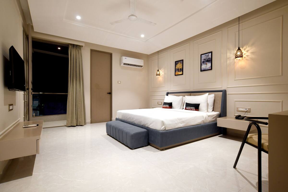 Una habitación de hotel moderna con una cama grande, un escritorio, un televisor de pantalla plana y una ventana con cortinas.