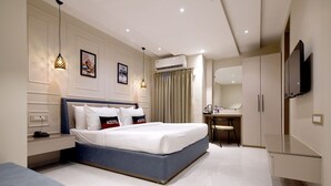 Quarto de hotel moderno com uma cama grande, mesas de cabeceira, escrivaninha e televisão.