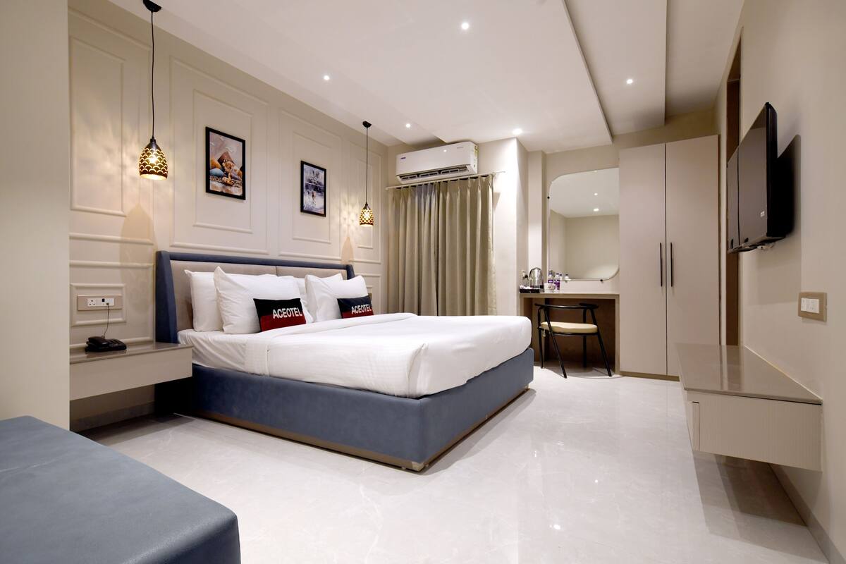 Una habitación de hotel moderna con una cama grande, mesitas de noche, un escritorio y un televisor.