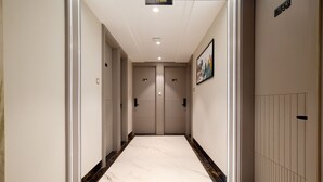 Corredor com piso de mármore, duas portas e uma placa indicando o andar.