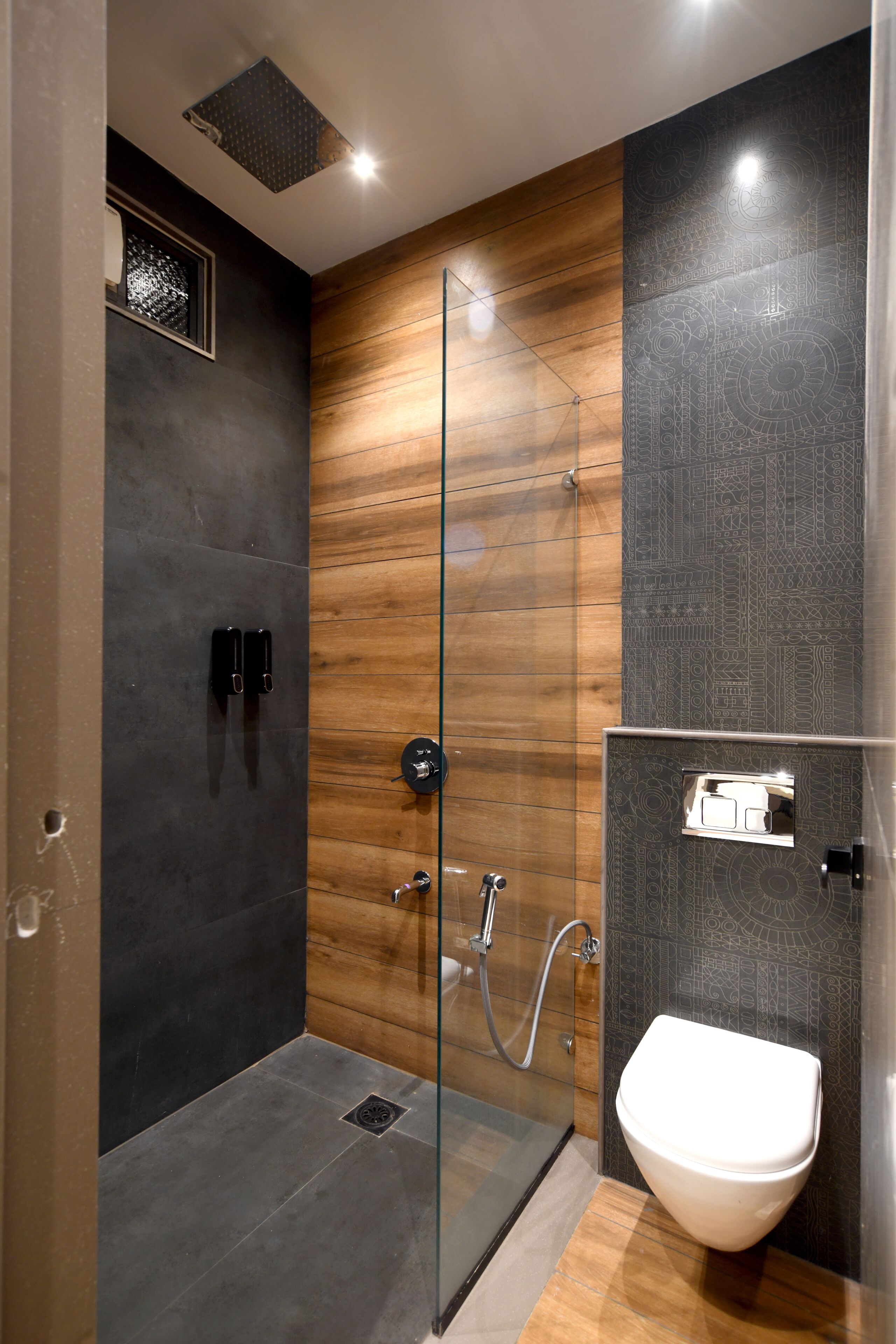 A modern bathroom with a glass shower enclosure, a wooden panel wall, and a white sink.