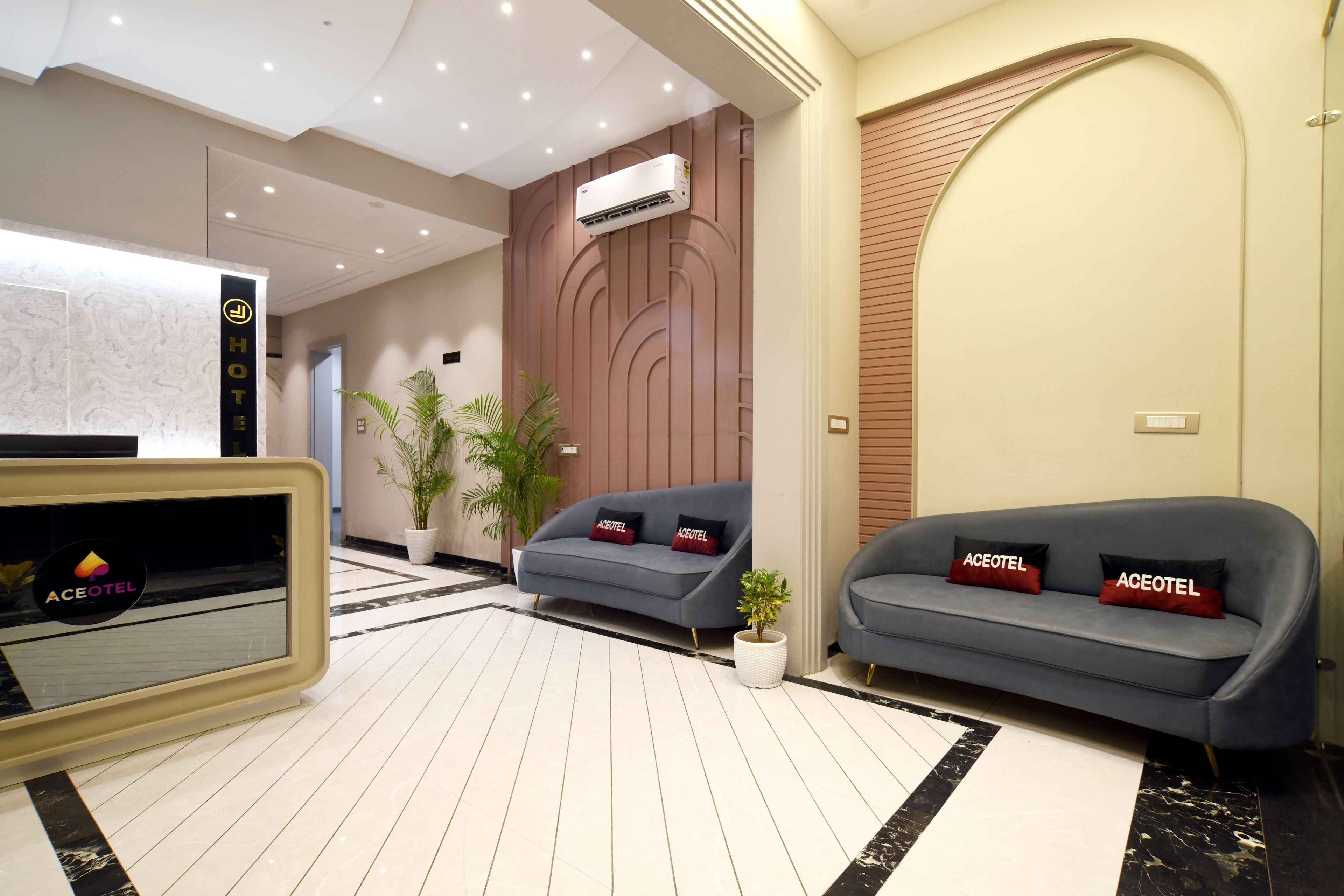 Eine moderne Hotelhalle mit einer Rezeption, Sofas, Topfpflanzen und einem großen Spiegel.