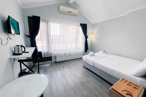 A small, well-lit room with a bed, a desk, a chair, a white table, and a window with curtains. - Taksim Centre Geneva Hotel (Istanbul)