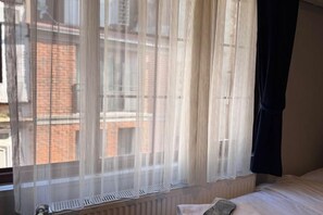 A room with a bed, a window with sheer curtains, and a radiator below the window. - Taksim Centre Geneva Hotel (Istanbul)