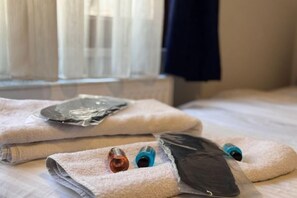 A bed with a white sheet, a folded towel, and two bottles on it. - Taksim Centre Geneva Hotel (Istanbul)