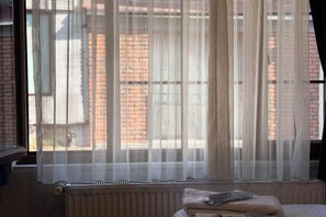 A room with a window, a radiator, and a bed with pillows. - Taksim Centre Geneva Hotel (Istanbul)