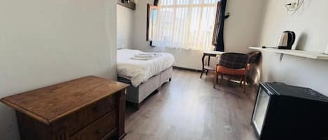 A bedroom with a bed, a wooden nightstand, a chair, and a television.