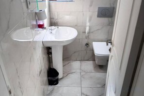 A bathroom with a white sink, a toilet, and a trash bin. - Taksim Centre Geneva Hotel (Istanbul)