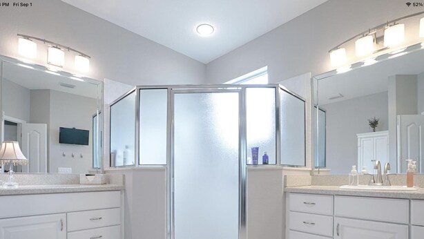 A modern bathroom with a walk-in shower, double sinks, and a large mirror. - Designer 3 bedroom high-end home with walking distance to Lake Sumter Landing (The Villages)