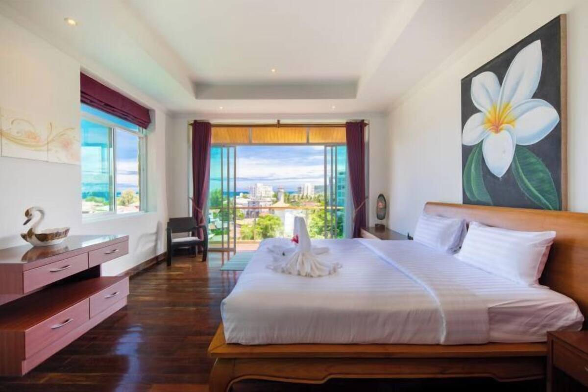 Une chambre d’hôtel moderne avec un grand lit, une vue sur la ville et un tableau représentant une fleur accroché au mur.