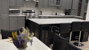 A modern kitchen with grey cabinets, stainless steel appliances, and a central island with bar stools. - Home with Park View on Yonge St Newmarket (Newmarket)