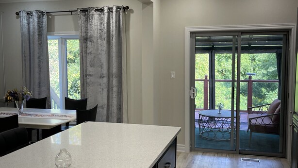 A kitchen with a large island, a dining area with a table and chairs, and a sliding glass door leading to an outdoor patio. - Home with Park View on Yonge St Newmarket (Newmarket)