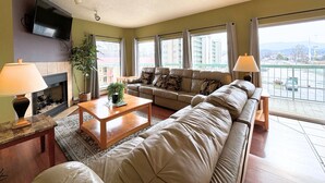 A living room with a sofa set, a coffee table, a fireplace, and a TV mounted on the wall.