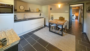 A modern kitchen with white cabinets, a black countertop, and a dining area with a wooden table and chairs.