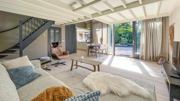 A modern living room with a sofa, coffee table, and a dining area with chairs.