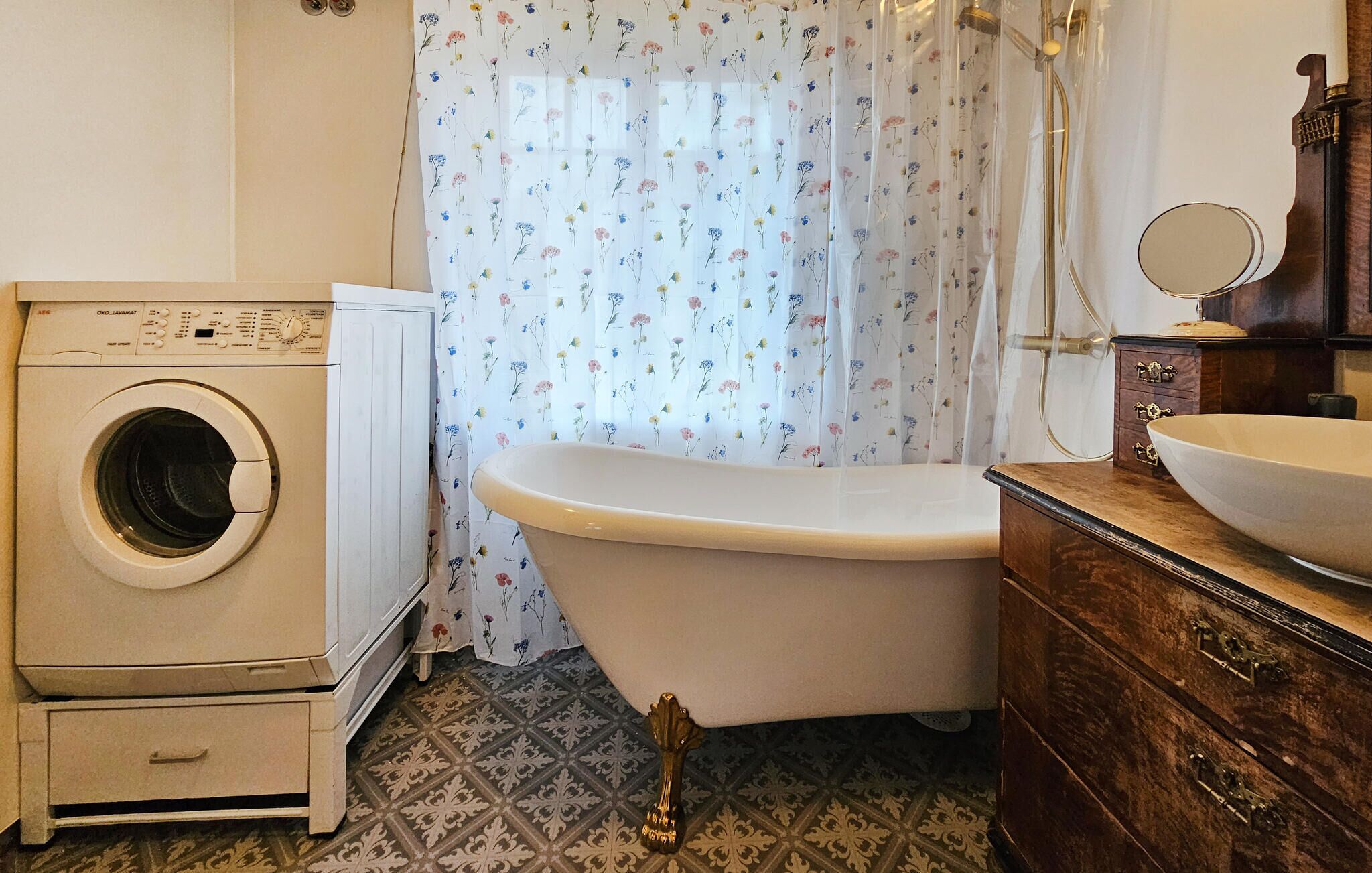 A compact bathroom with a washing machine, a bathtub, and a wooden vanity with a mirror.