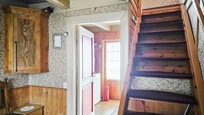 Un interno in legno con una scala, un armadio in legno e una porta che dà su un'altra stanza.