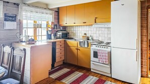 Una cucina con mobili in legno, un frigorifero bianco, un fornello e un forno a microonde.
