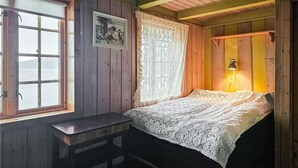 Una camera in una baita di legno con un letto, una finestra vista e una lampada.