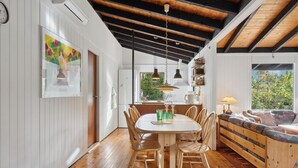 A dining area with a wooden table and chairs, a kitchen with a window, and a cozy seating area with a sofa and cushions. - 3 bedroom awesome home in Gilleleje (Gilleleje)