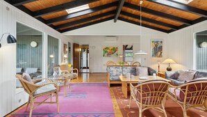 A spacious living area with a high ceiling, wooden beams, wicker furniture, and colorful rugs. - 3 bedroom awesome home in Gilleleje (Gilleleje)