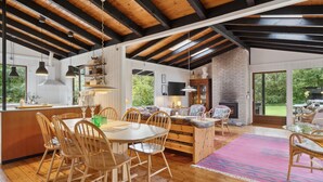 A spacious dining area with wooden chairs and a large table, a cozy seating area with wicker chairs, and a fireplace. - 3 bedroom awesome home in Gilleleje (Gilleleje)