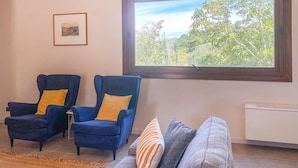 A living room with two blue armchairs, a framed picture on the wall, and a window with a view of trees. - 2 bedroom beautiful home in Modica (Modica)