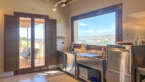 A modern kitchen with a large window, stainless steel appliances, and a view of a cityscape. - 2 bedroom beautiful home in Modica (Modica)