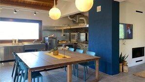 A modern kitchen with stainless steel appliances, a dining area with a wooden table and blue chairs, and a blue accent wall. - 2 bedroom beautiful home in Modica (Modica)