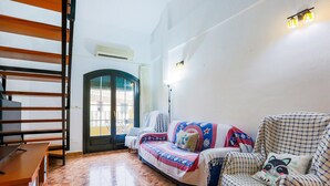 Ein Wohnzimmer mit einer Couch, einem Sessel, einem Holztisch und einer Treppe.