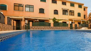Ein Schwimmbecken mit gefliestem Rand, umgeben von einem mehrstöckigen Gebäude mit pflaumengewebter Fassade und grünen Fensterläden.