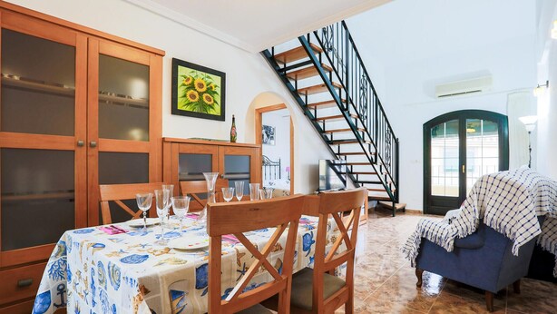 Ein Essbereich mit Tisch für vier Personen, einer Treppe und Blick ins Freie.