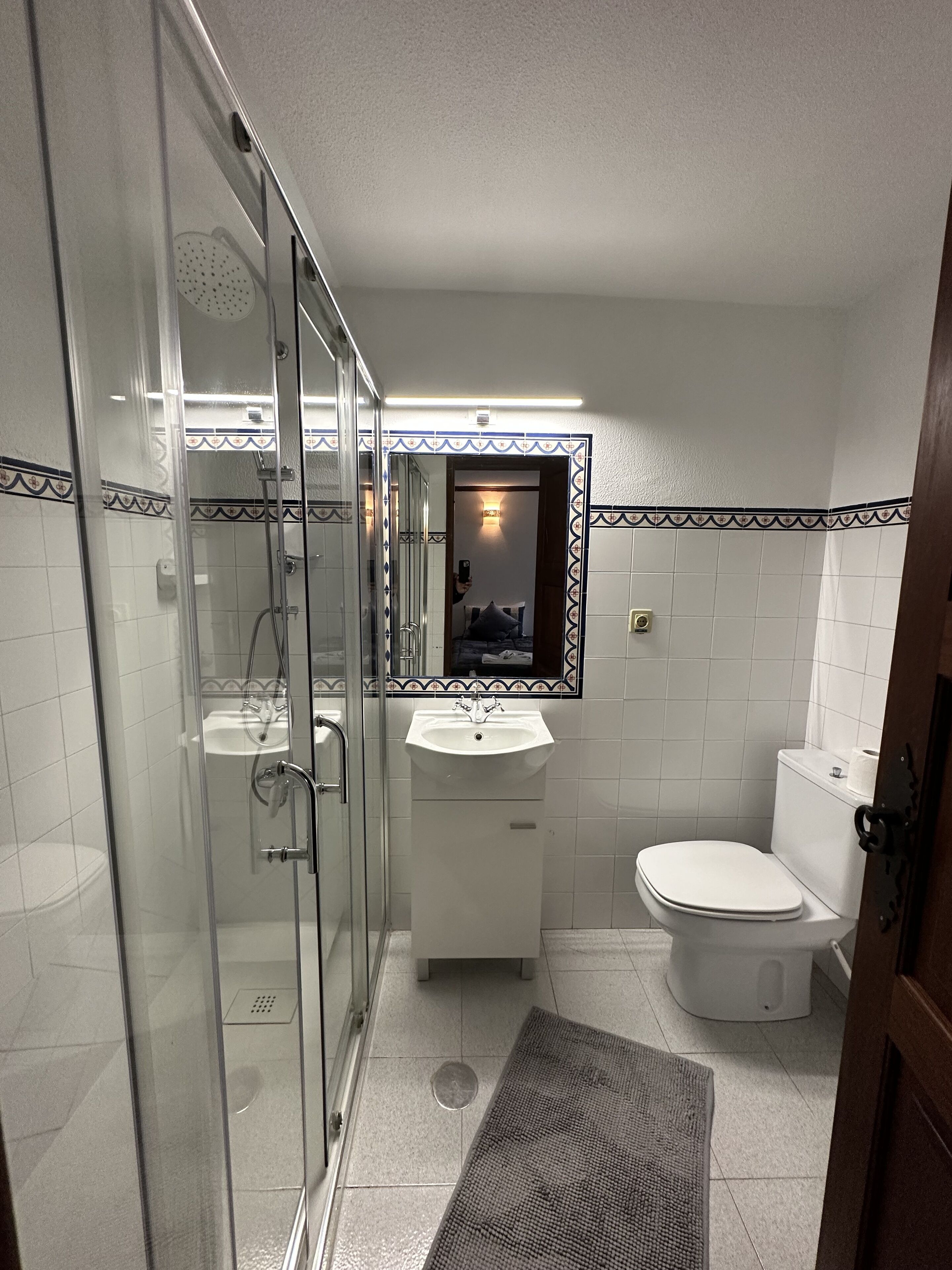 A bathroom with a glass shower enclosure, a sink, and a toilet.