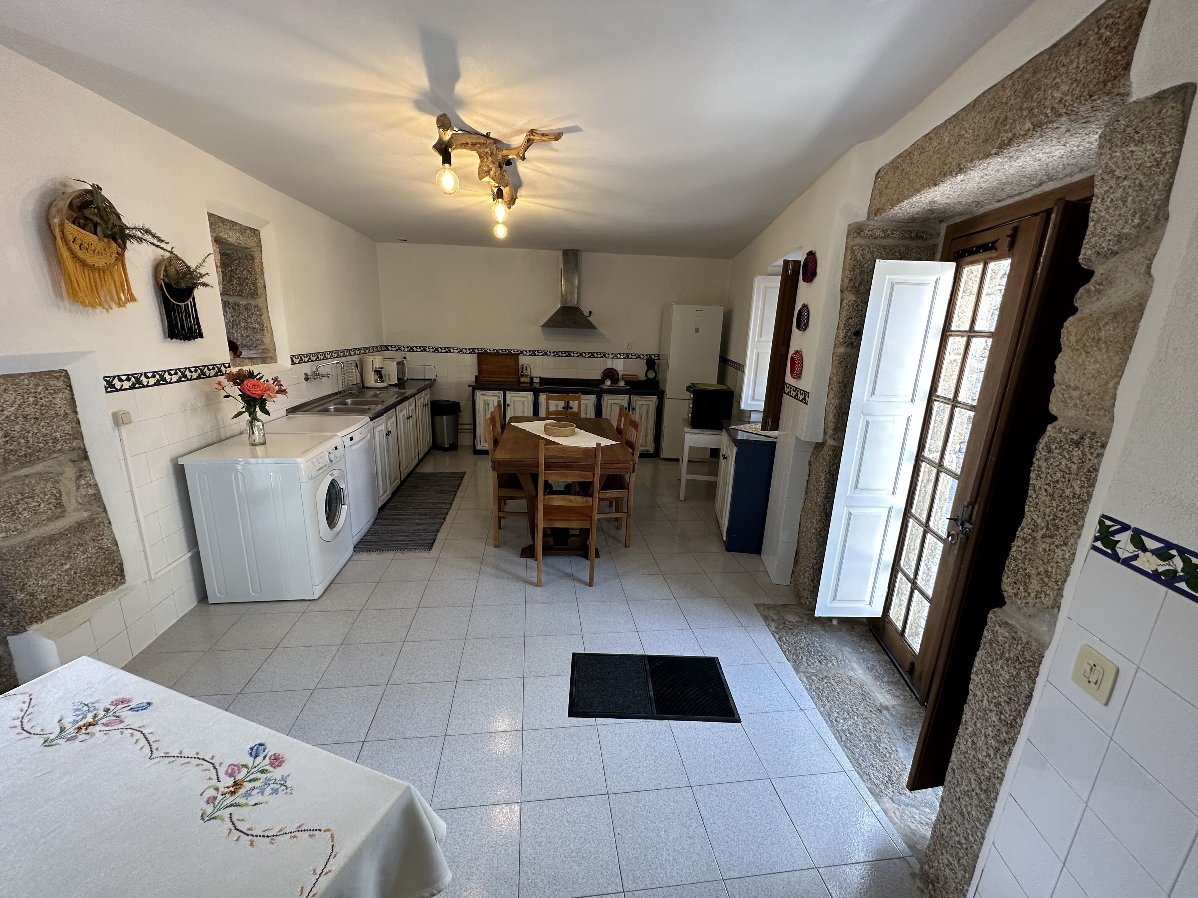 A compact kitchen with a dining area, a washing machine, and a dining table with a floral tablecloth.