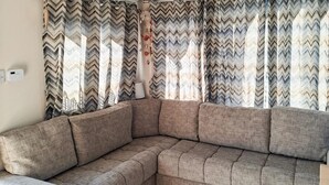 Een hoekbank in een woonkamer met een gordijn met een zigzagpatroon.