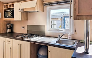 A compact kitchen with a gas stove, sink, and a window overlooking a residential area.