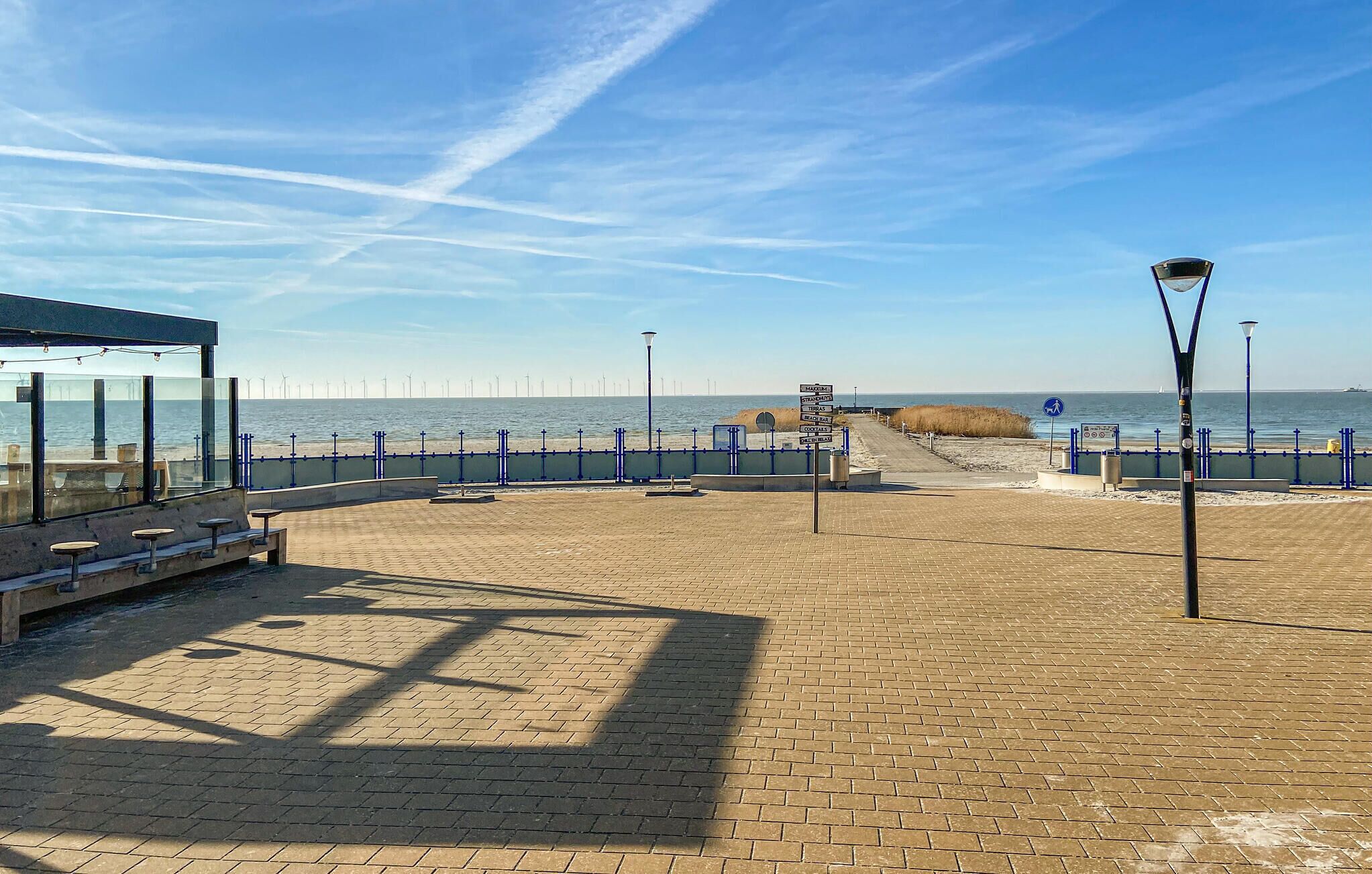 Een verharde promenade met banken en een uitkijkpunt over de zee.